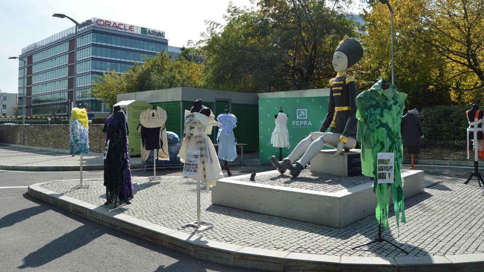 Ținute create din textile recuperate, expuse pe manechine în fața Clădirii A din Oregon Park, lângă panoul FEPRA