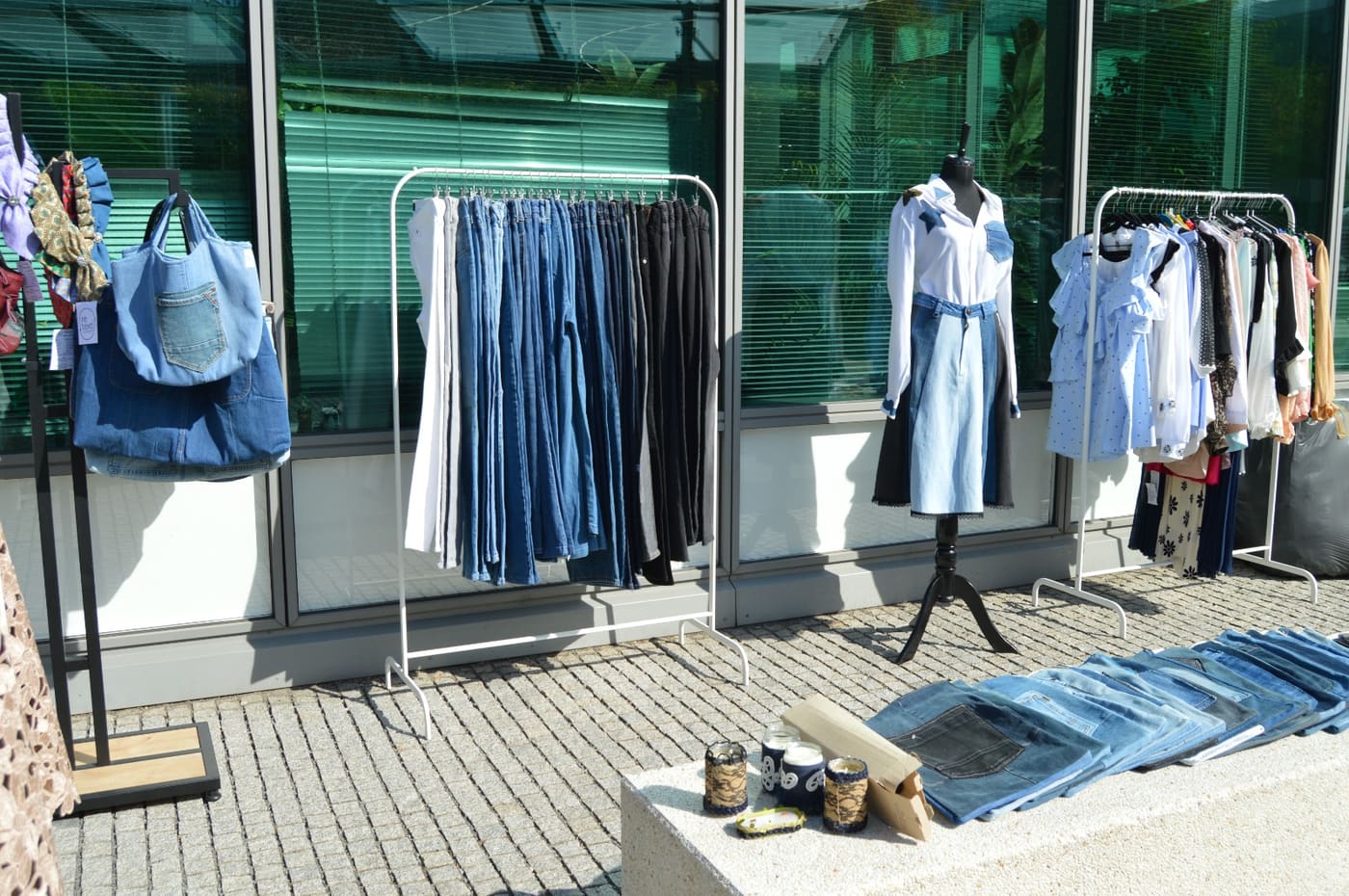Magazinul în aer liber: blugi, cămăși și genți din denim reconstruit, pe stendere în fața clădirii