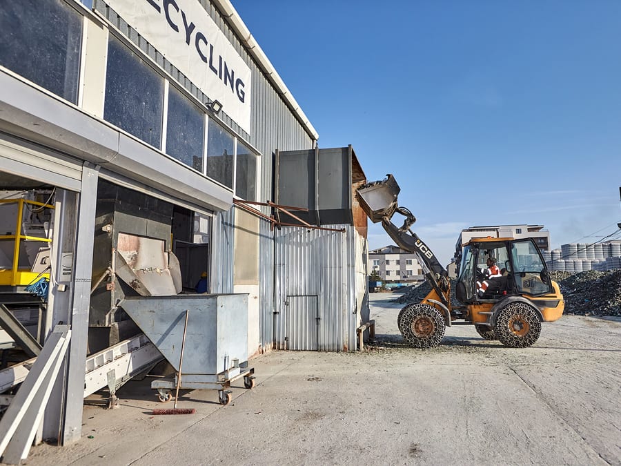 Feeding: the front loader tips glass waste into the line's hopper
