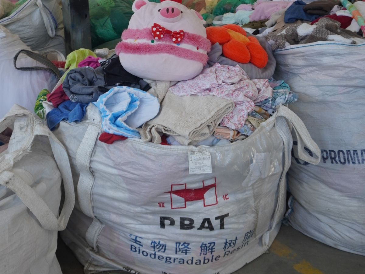 Saci mari cu haine și textile colectate, în hala de sortare